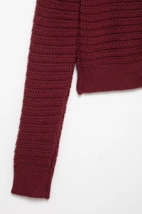 Detail view of burgundy textured knit fabric and ribbed cuffs on a women sweater