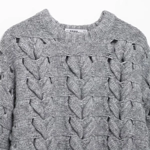 Pull femme en maille grise à col rond avec des motifs torsadés en forme de cœur