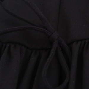 Close-up of black mini dress featuring a bow-tie knot and elegant ruched fabric texture