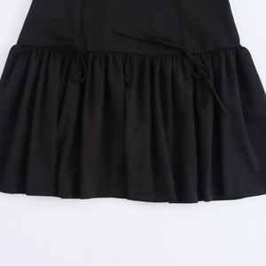 Detail view of black mini dress with pleated ruffles and decorative tie strings