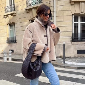 Women's beige faux shearling jacket with brown leather trim and casual blue denim pants