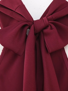 Detail view of large bow on burgundy halter maxi dress with premium satin finish