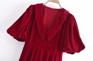 Détail d'une robe en velours rouge avec décolleté en V et manches bouffantes élégantes