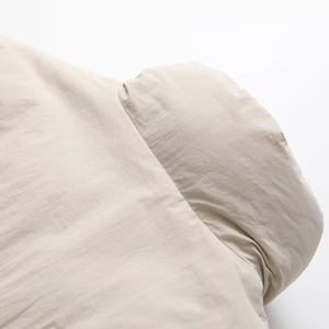 Detail of beige puffer jacket featuring knit sleeve stitching and premium water-repellent fabric