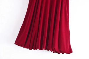Détail du tissu en velours plissé d'une robe bordeaux avec un ourlet bouffant