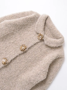 Détail de la veste en maille avoine avec boutons fleurs 3D et détails perles