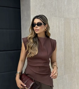 Detail showing the pleated shoulder pads and fabric texture of the slim brown top
