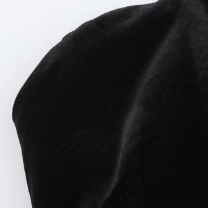 Close-up of black velvet fabric texture showing premium silky fiber detail on the dress