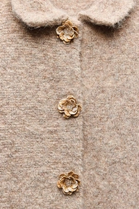 Détail du manteau en maille avoine avec boutons floraux et texture mohair douce