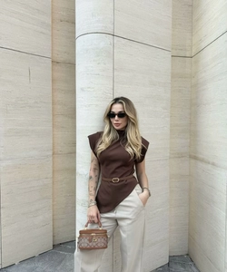 Street style shot of a woman in brown shoulder-padded top and cream trousers