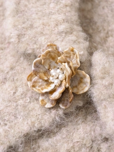 Gros plan d'une broche fleur en résine vintage avec perles sur tricot beige