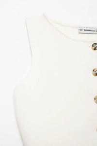 Detail view of ivory knit vest with decorative golden buttons and vertical rib texture