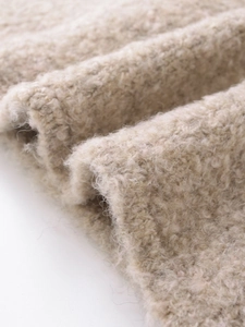Gros plan sur la texture en fausse fourrure beige de cette veste élégante pour femme