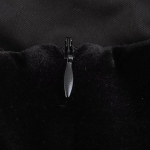 Detail of hidden zipper on elegant black velvet dress with smooth texture and finish