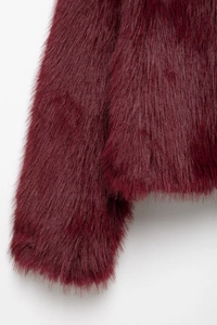Macro shot of dense burgundy faux fur texture on the stylish long sleeve coat