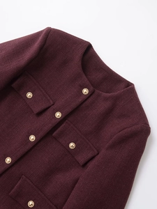 Detail of burgundy tweed jacket featuring textured golden buttons and elegant crew neck