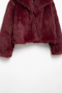 Detail of burgundy faux fur texture on a long-sleeved jacket with a wide lapel collar