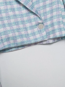 Detailed close-up of lavender and blue tweed texture with a silver button on a blazer