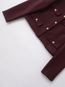 Detail of burgundy tweed jacket featuring textured fabric and golden relief buttons