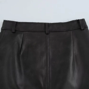 Détail de la taille d'une jupe noire en similicuir avec passants de ceinture et bord franc