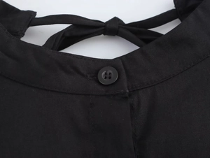 Detail of round neckline with black button and bow tie ribbon on sleeveless dress