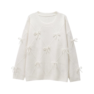 Detail of cream knit sweater showing textured diamond pattern and delicate bow accents