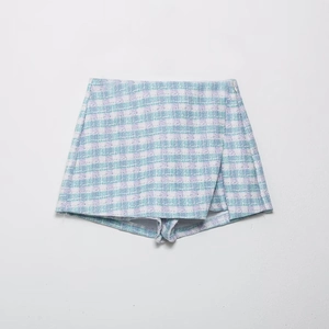 Detail view of woven light blue and purple tweed skort with wrap design and texture