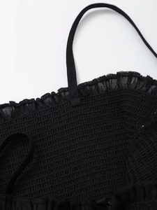 Detailed close-up of black smocked dress bodice with elastic ruffles and thin straps
