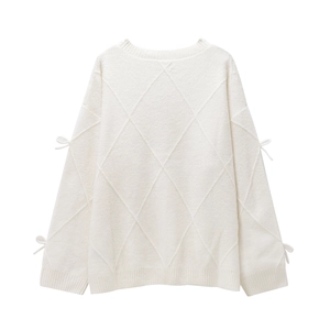 Detail of white knit sweater with large diamond weave texture and bow accents on sleeves