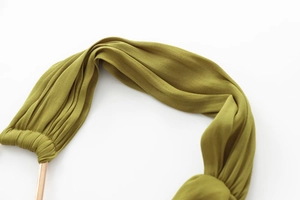 Detail of olive green pleated fabric with elegant gold metal cylindrical hardware buckle