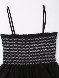 Detail of black summer dress with smocking elastic bodice and white embroidery stitching