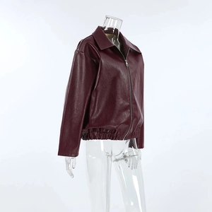 Detail of wine red faux leather jacket showing zipper closure and elastic hem