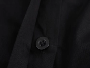 Close-up detail of smooth black fabric texture and a matching four-hole round button