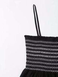 Detail of black camisole dress with white smocked embroidery and thin straps