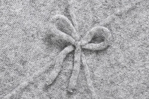 Macro shot of gray knitted bow detail showcasing high-quality polyester fiber texture