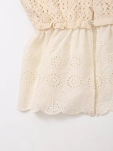 Detailed close-up of beige crochet lace top with hollow embroidery and scalloped hem