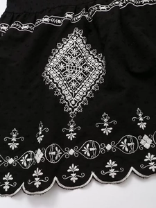 Detail of black Swiss dot fabric with ethnic geometric embroidery and scalloped edge finish