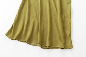 Detail of olive green satin fabric showing smooth texture and draped hemline quality