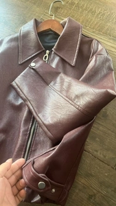 Detail view of burgundy leather jacket featuring lapel collar and silver snap cuffs