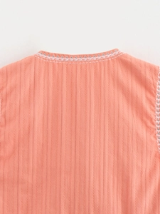 Detailed close-up of coral pink cotton linen vest featuring floral embroidery and stitching