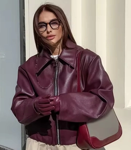 Detail of burgundy oversized faux leather jacket with classic lapel and metallic zipper