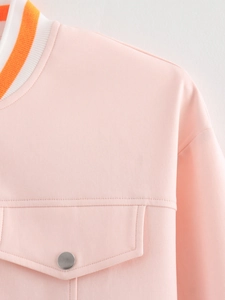 Close-up of pink jacket with orange ribbed collar, silver buttons and flap pocket detail