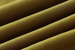 Detailed macro view of olive green satin fabric texture with elegant draped folds