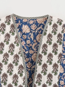 Detail of reversible quilted vest featuring floral patterns and striped contrast piping