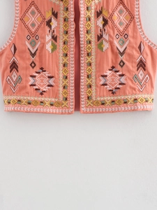 Close-up of geometric embroidery and quilted texture on coral linen vest jacket