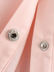 Detailed macro view of silver metal snap buttons on premium light pink fabric texture
