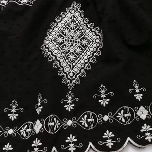 Close-up of black summer dress featuring white geometric embroidery and scalloped lace hem