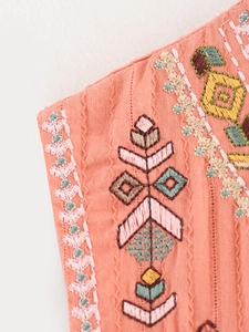 Detailed macro view of geometric ethnic embroidery on breathable cotton linen vest