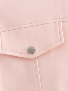 Detail of pink jacket showing pocket flap with matte silver button and double stitching