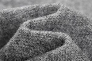 Close-up of grey knitted fabric texture showing soft wool blend weave and material detail